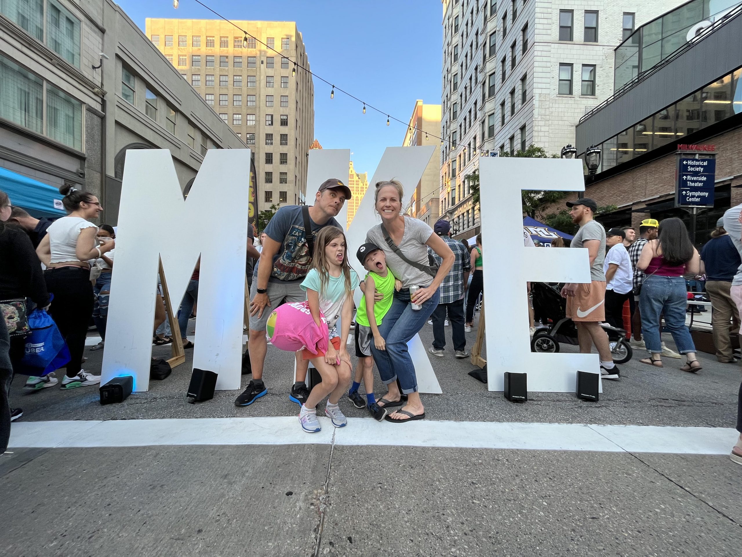 Family of 4 in front of a MKE sign in Milwaukee, WI