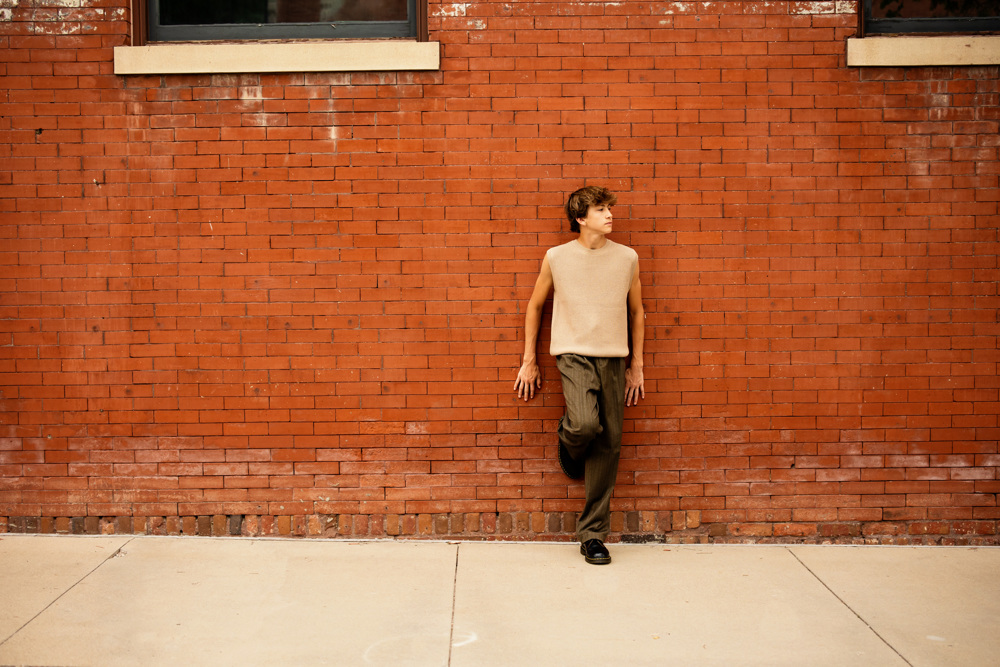 Senior boy leaning against a brick wall