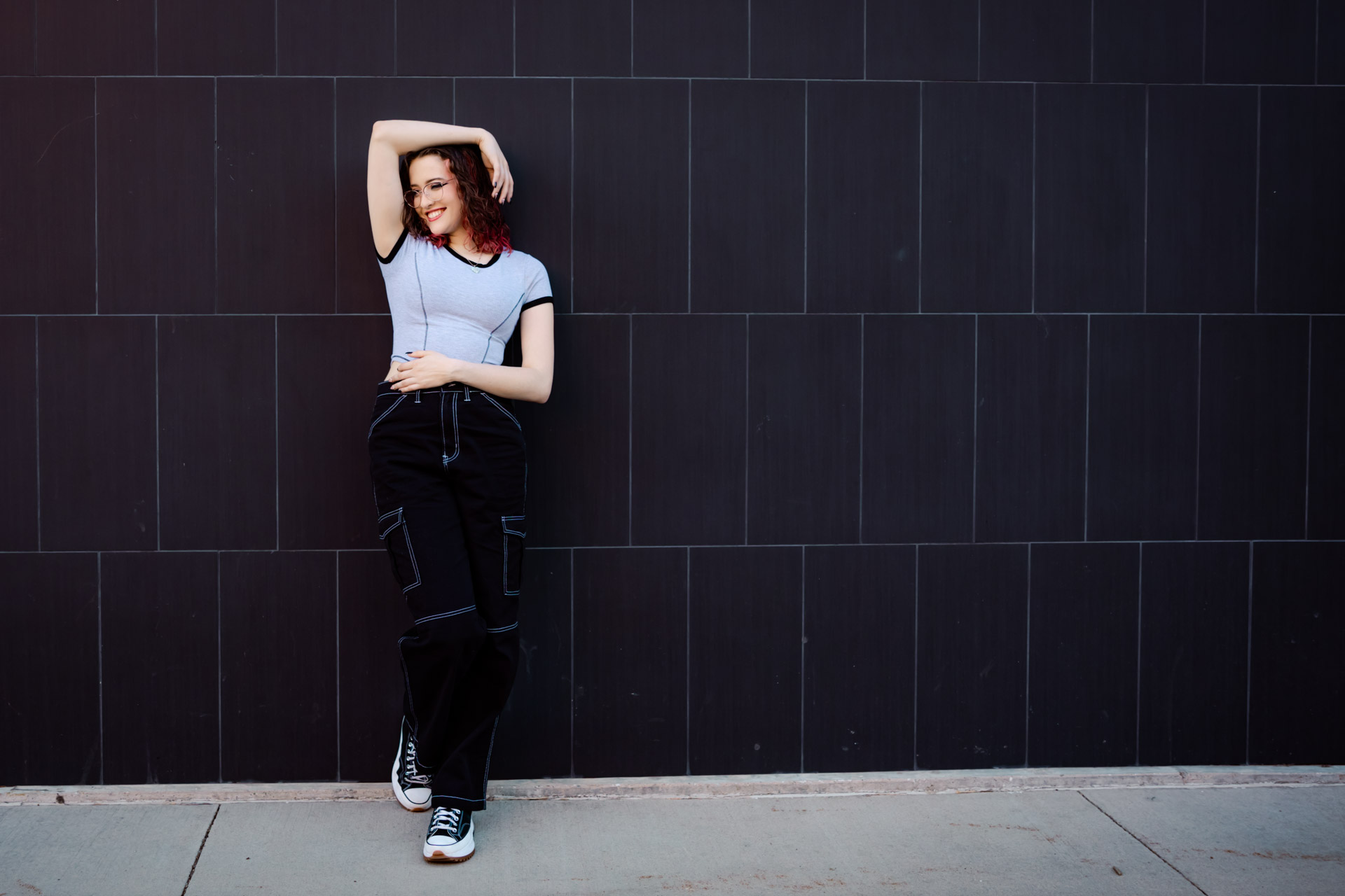 Senior girl standing along a gray wall