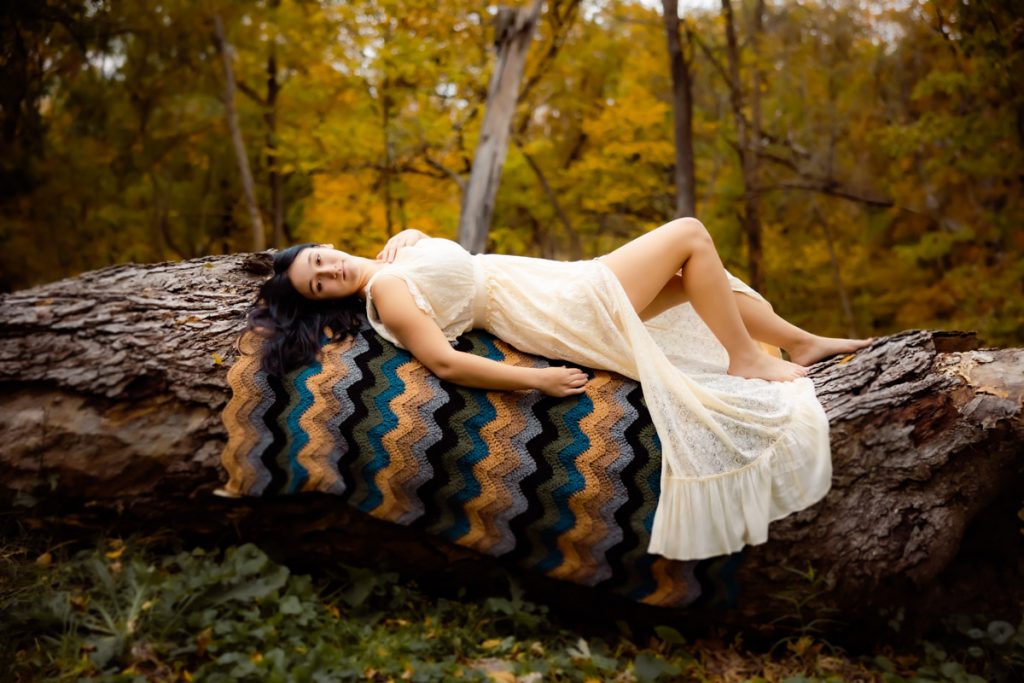 Girl in ecru dress lying on a fallen tree
