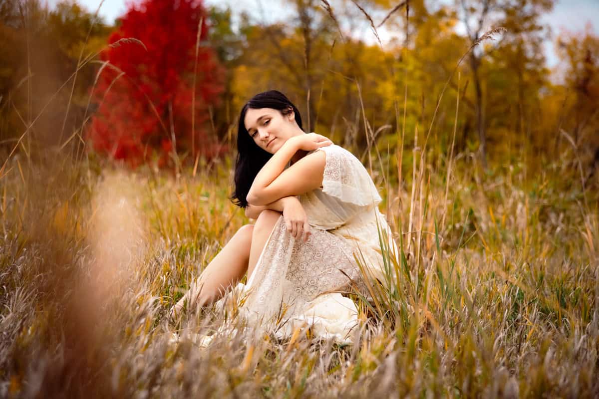 Senior in grassy field in a long dress