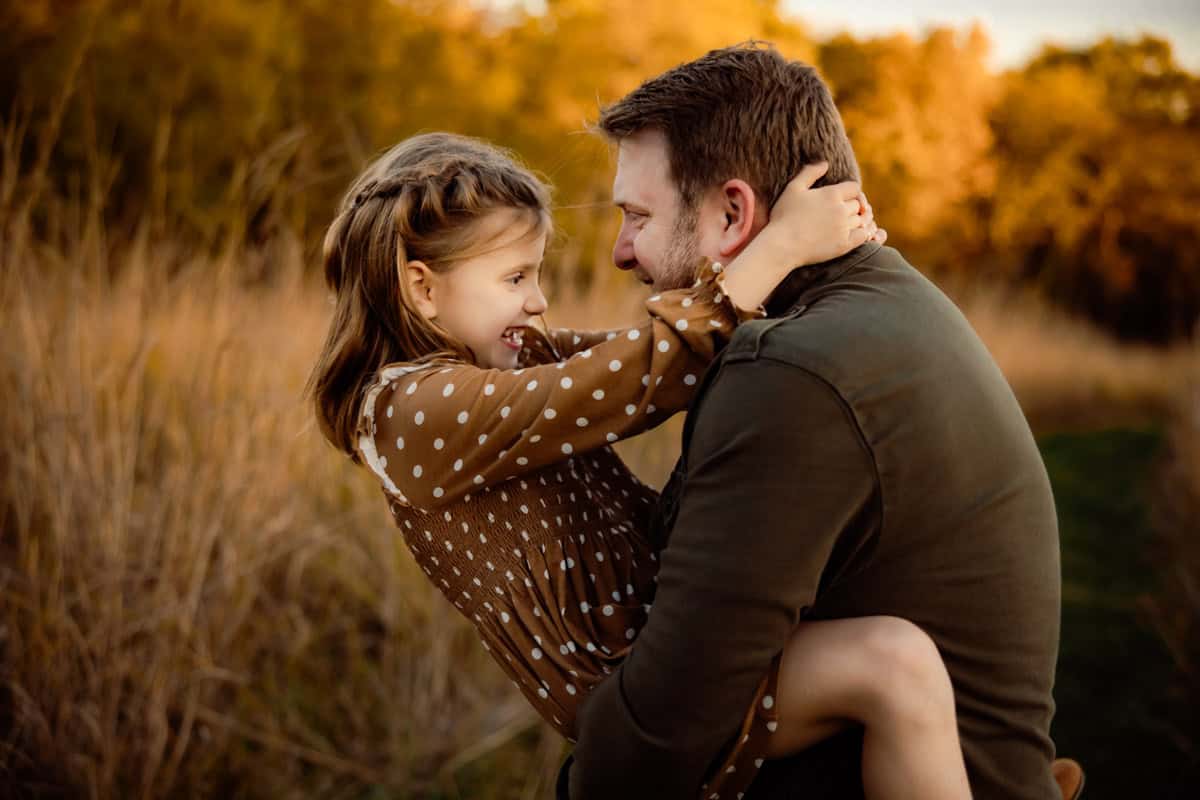 Dad holding young daughter in his arms