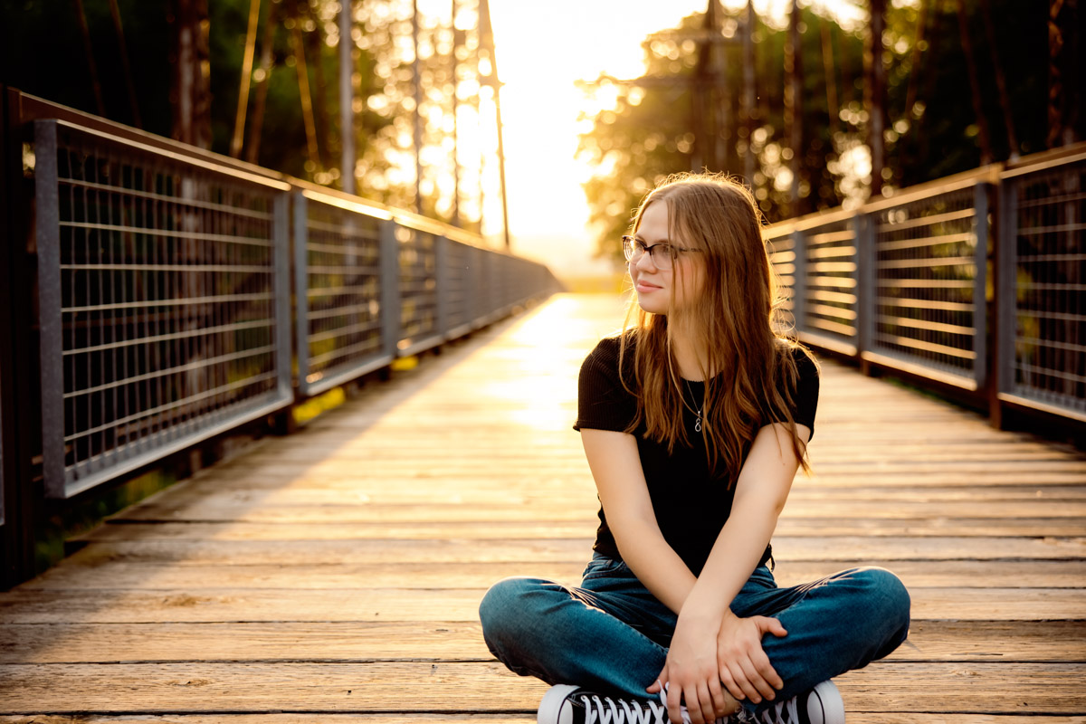 senior girl sitting on a bridge in the sunset