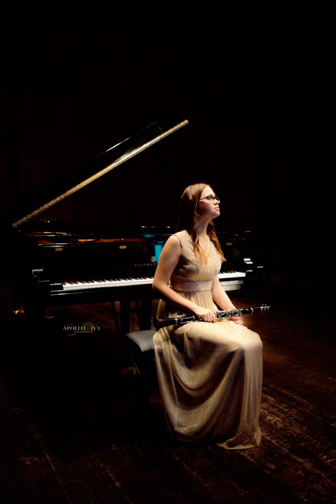 Senior girl in a prom dress sitting at a piano with clarinet