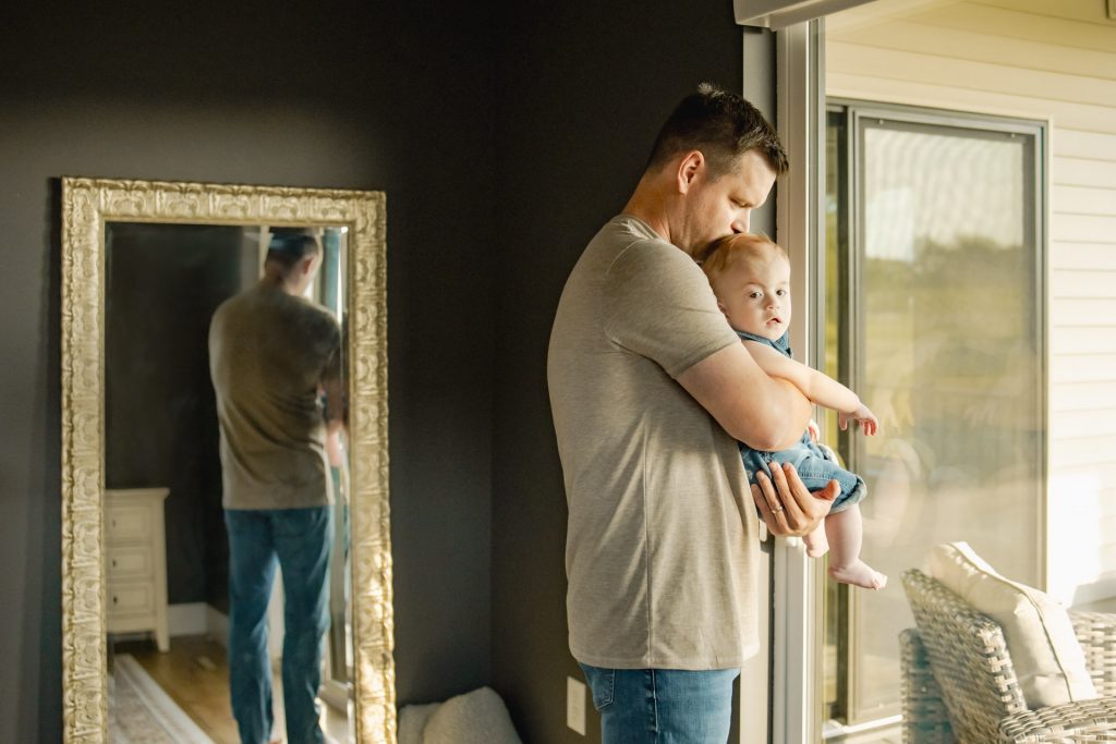 Dad holding baby standing by window