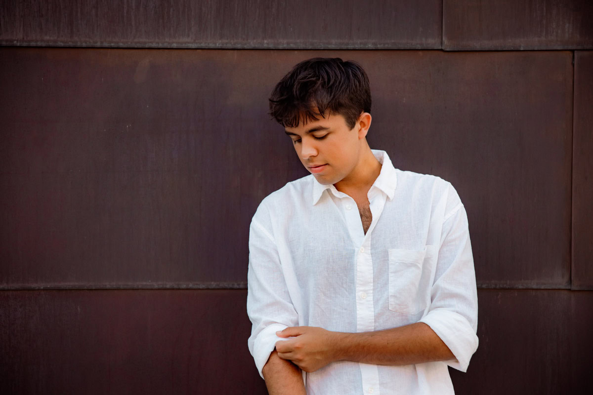 Senior boy in white button down against a copper building