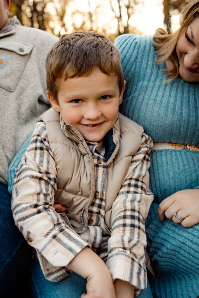 What to wear for cold-weather outdoor photos Photo of toddler boy wearing a large puffy beige vest seated on his mother's lap. The vest is bunching up around his ears.