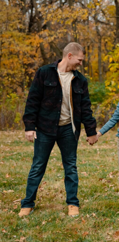 What to wear for cold-weather outdoor photos Man wearing a t-shirt, shacket, jeans, and boots during cold-weather outdoor photos.