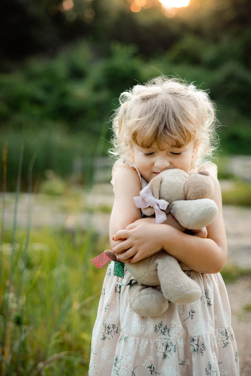Toddler girl hugging her teddy bear with her eyes squeezed shut