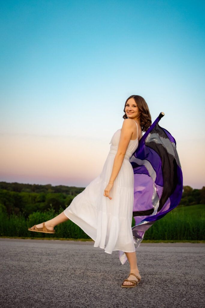Beginner's guide to senior pictures in Iowa Senior girl in white dress with color guard flag