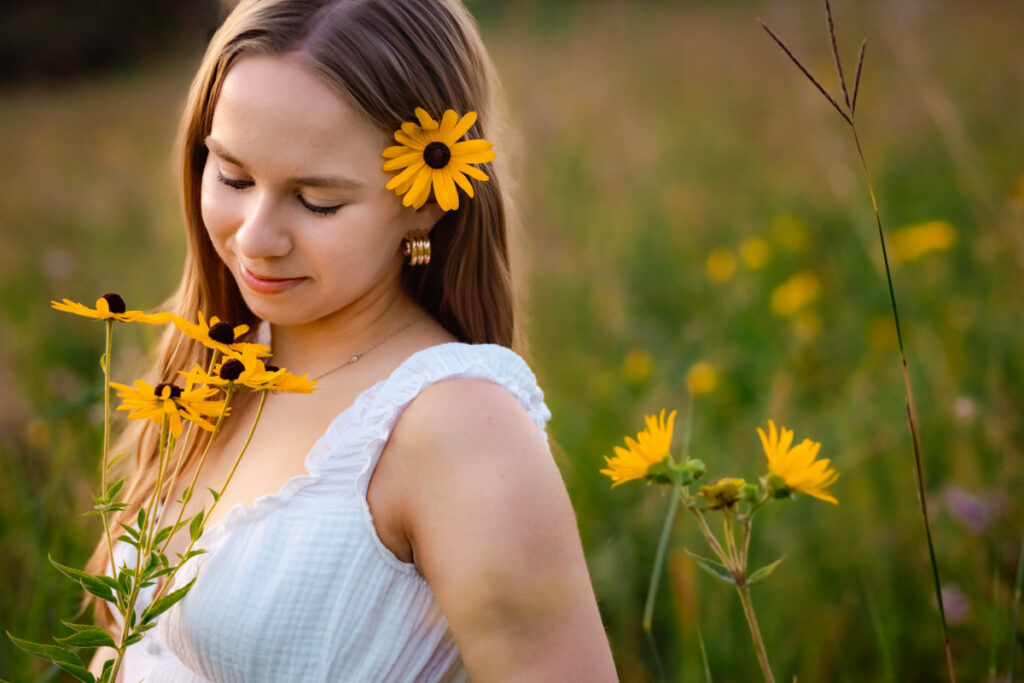 Beginner's guide to senior pictures in Iowa Senior holding flowers in a white dress in a flower field.
