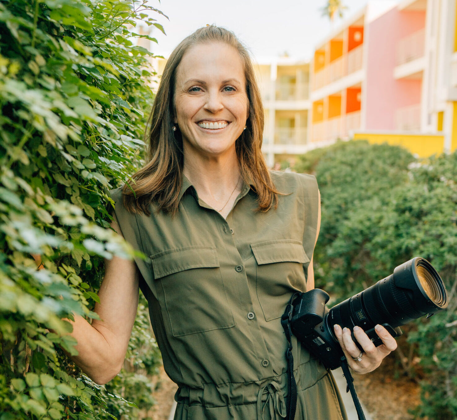 Photographer Lydia Fine standing by an ivy-covered wall.