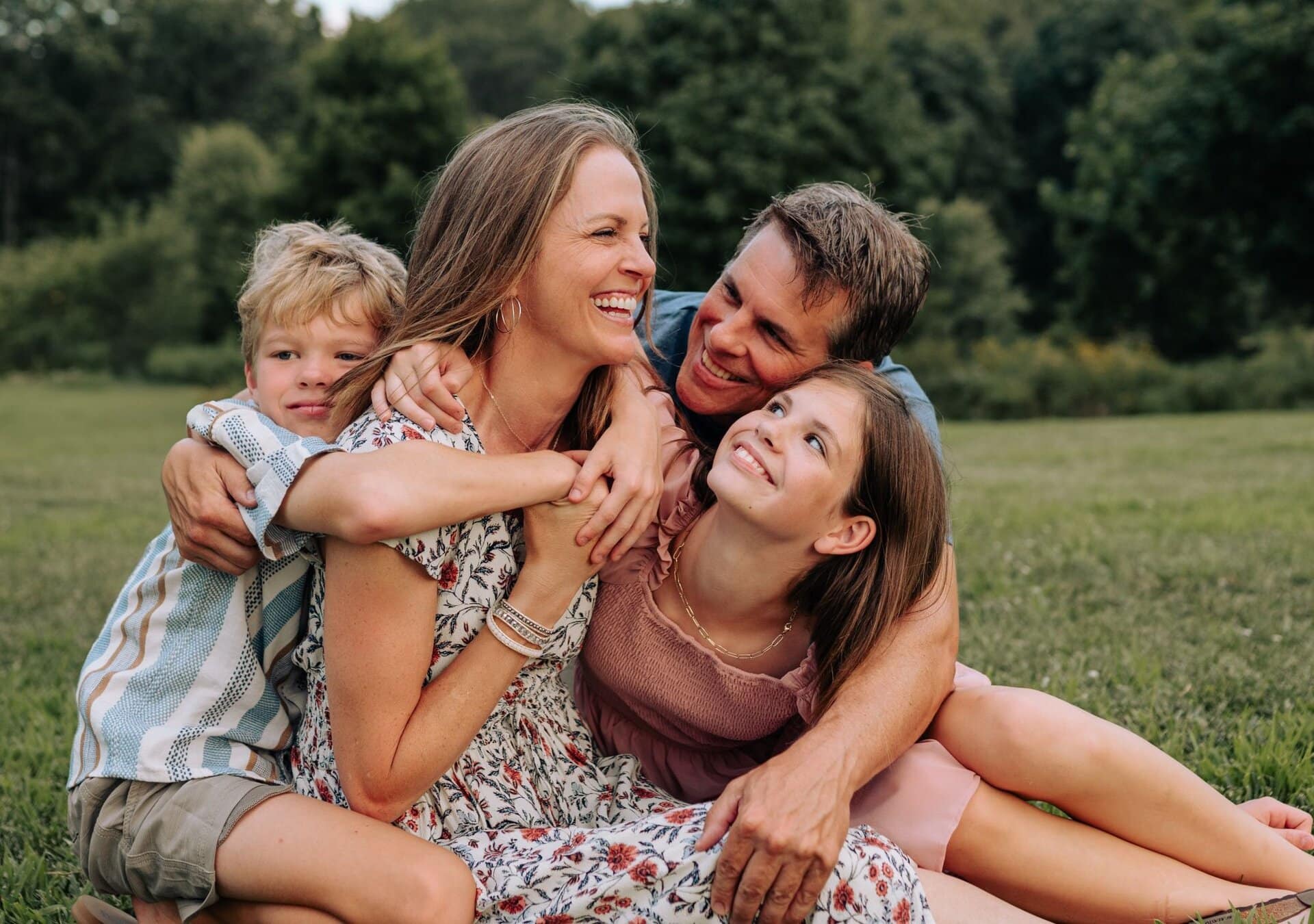 Lydia and her family seated on the grass on a summer day in a park during family photos in St Louis